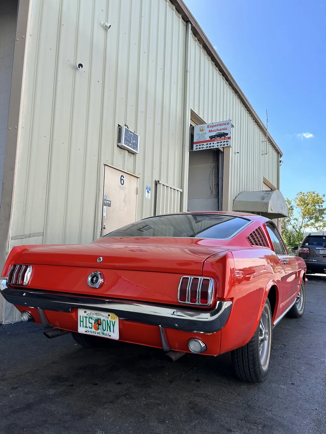A red classic Ford Mustang parked outside the Garage 66 shop